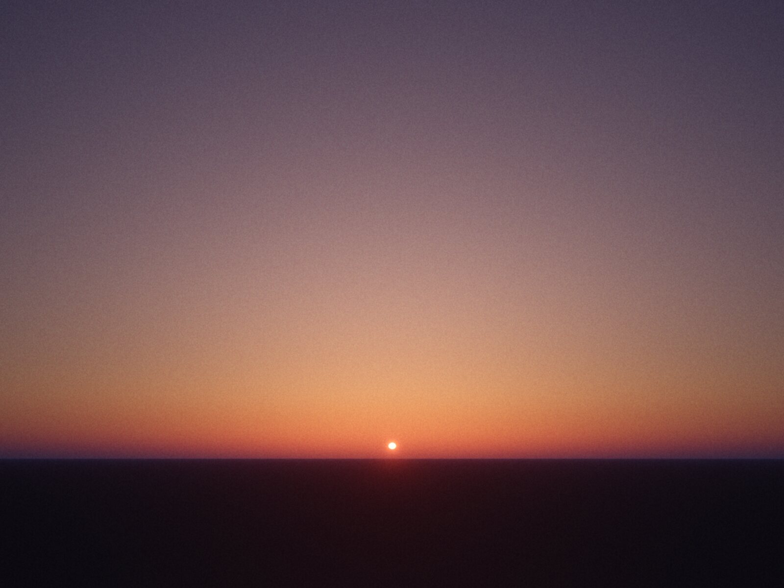A rendered sunrise, printed as a black halftone on kraft: the dots thin out into a glow around the sun on the horizon.